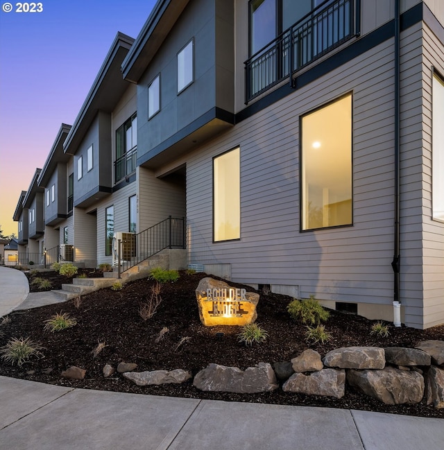 property exterior at dusk featuring a balcony, a fire pit, and central AC