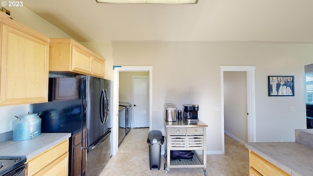 kitchen featuring light brown cabinetry, black refrigerator, and range