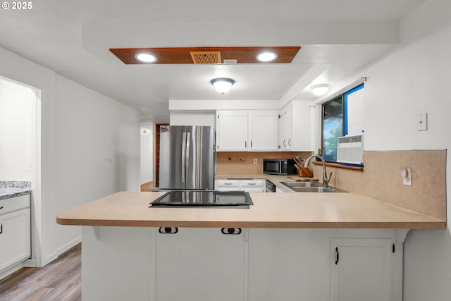 25191 Berry Ln, Veneta, OR 97487 - kitchen with black appliances, a peninsula, light countertops, light wood finished floors, and white cabinetry