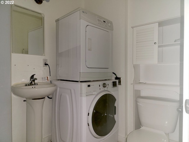 clothes washing area featuring sink and stacked washer and clothes dryer