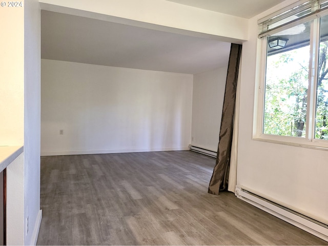 empty room featuring hardwood / wood-style flooring and a baseboard radiator