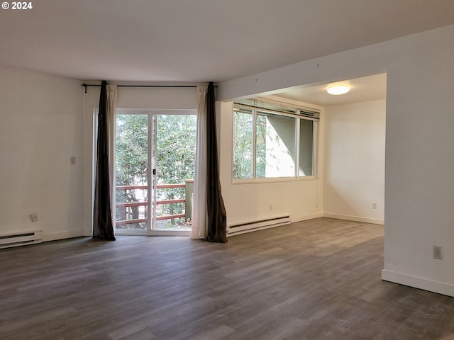 empty room featuring dark wood-type flooring and a baseboard heating unit