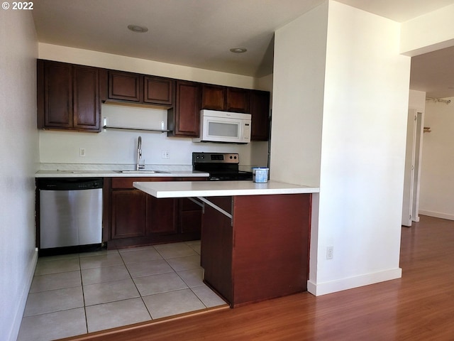 kitchen featuring dishwasher, sink, kitchen peninsula, black / electric stove, and light tile patterned floors