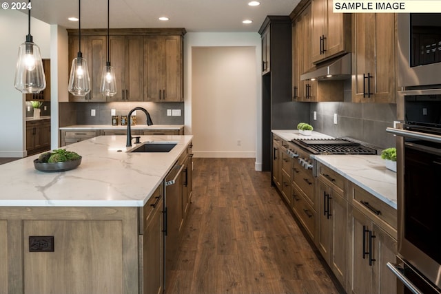 kitchen with an island with sink, dark wood-type flooring, sink, backsplash, and light stone counters