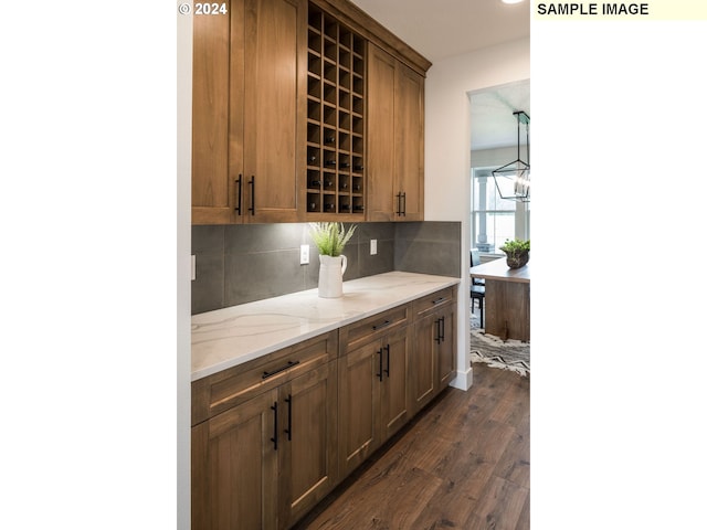 kitchen with decorative light fixtures, a chandelier, light stone counters, tasteful backsplash, and dark hardwood / wood-style flooring