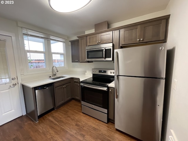 kitchen with stainless steel appliances, sink, dark wood-type flooring, and dark brown cabinetry