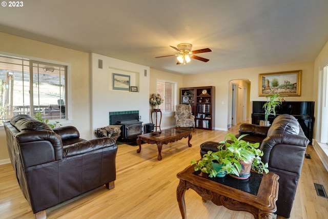 living room featuring a wood stove, light hardwood / wood-style floors, and ceiling fan