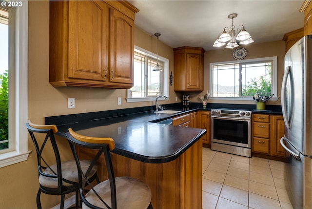 kitchen featuring an inviting chandelier, stainless steel appliances, pendant lighting, and kitchen peninsula