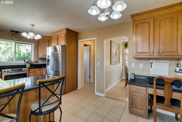 kitchen with an inviting chandelier, appliances with stainless steel finishes, pendant lighting, light wood-type flooring, and a breakfast bar area