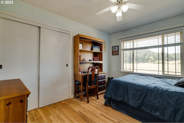 bedroom with a closet, light hardwood / wood-style floors, and ceiling fan