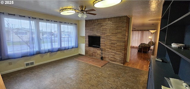 unfurnished living room with visible vents, a fireplace, and ceiling fan