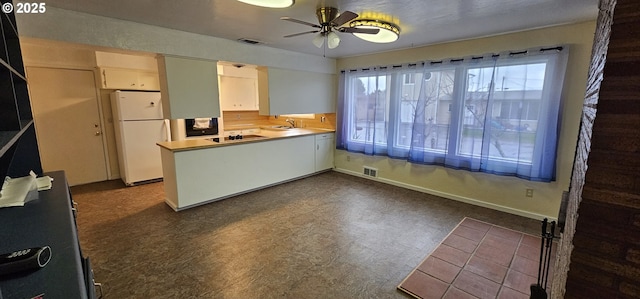 29545 Bailor St, Gold Beach, OR 97444 - kitchen with freestanding refrigerator, a peninsula, ceiling fan, dark floors, and a sink