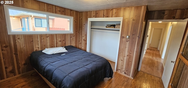 bedroom featuring a closet, wood finished floors, and wooden walls