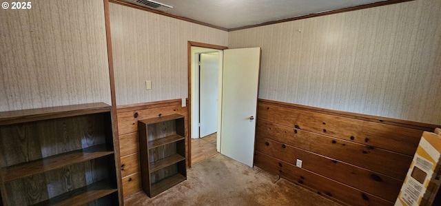 interior space with carpet, a wainscoted wall, visible vents, ornamental molding, and wallpapered walls