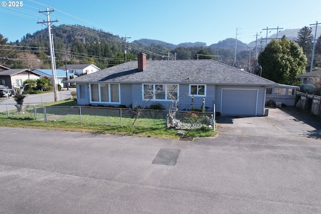 single story home with a front lawn, a fenced front yard, an attached garage, and a mountain view