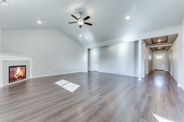 unfurnished living room featuring lofted ceiling, a fireplace, light wood-type flooring, and ceiling fan