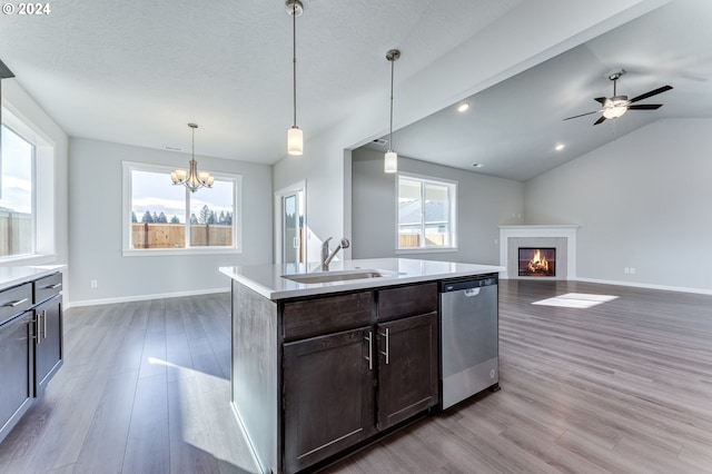 kitchen featuring sink, hardwood / wood-style floors, a tiled fireplace, decorative light fixtures, and stainless steel dishwasher