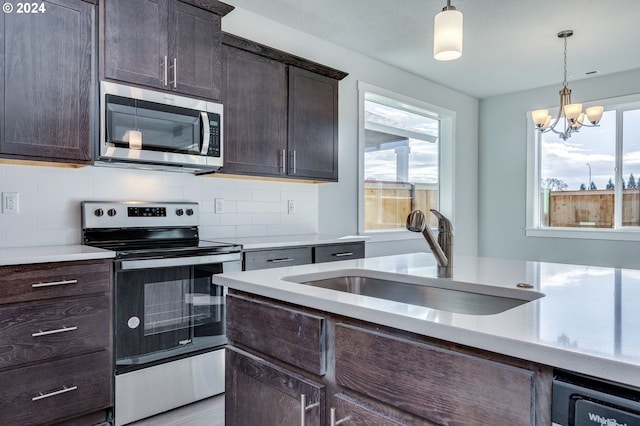 kitchen featuring a wealth of natural light, sink, appliances with stainless steel finishes, and a notable chandelier