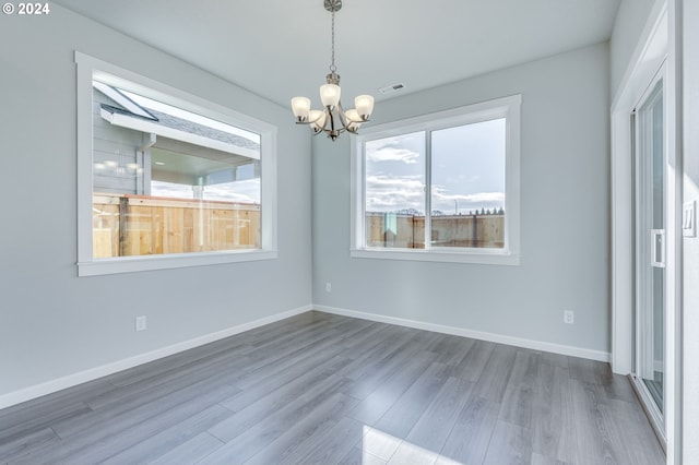 unfurnished dining area featuring hardwood / wood-style floors and a chandelier