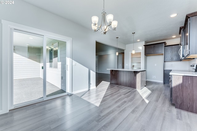 kitchen with white range, a kitchen island with sink, light hardwood / wood-style flooring, a notable chandelier, and decorative light fixtures