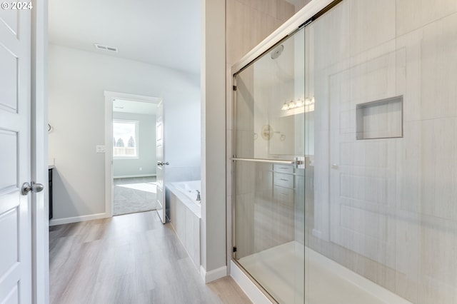 bathroom featuring hardwood / wood-style flooring and separate shower and tub