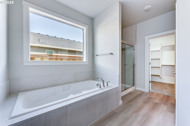 bathroom with hardwood / wood-style floors and shower with separate bathtub