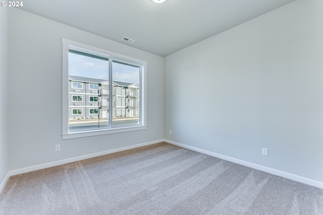 carpeted spare room featuring a textured ceiling