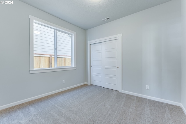 unfurnished bedroom with a closet, a textured ceiling, and carpet