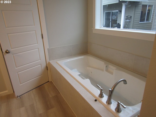 bathroom with tiled bath and hardwood / wood-style flooring