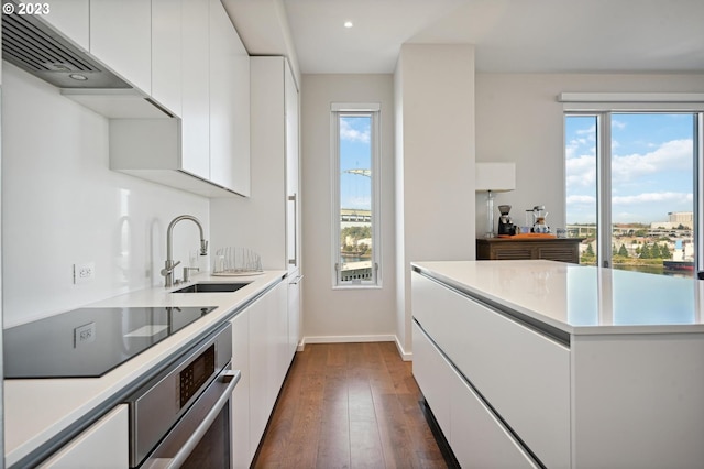 kitchen featuring dark hardwood / wood-style flooring, white cabinets, stainless steel oven, black electric stovetop, and sink