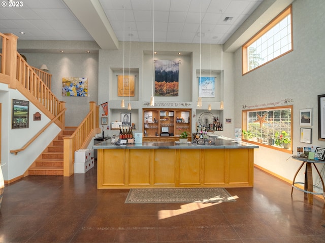 kitchen with a kitchen island, dark tile floors, decorative light fixtures, and a towering ceiling