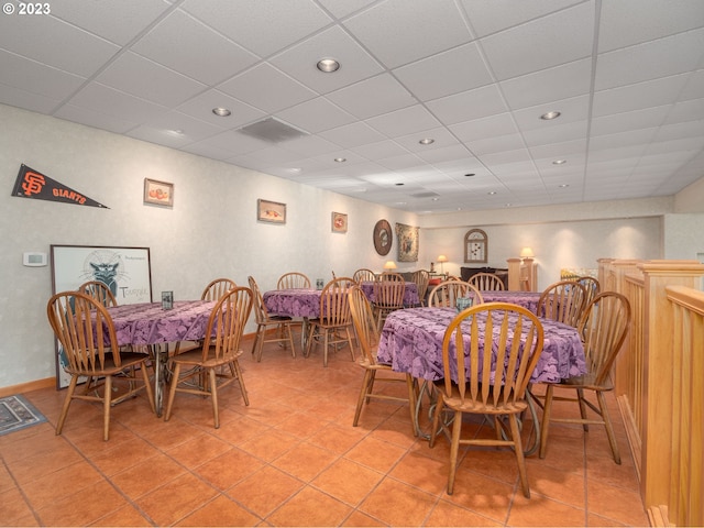 dining space featuring light tile flooring and a drop ceiling