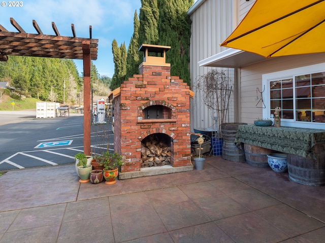 view of patio / terrace featuring an outdoor brick fireplace and a pergola