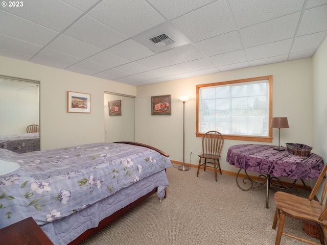 carpeted bedroom featuring a drop ceiling