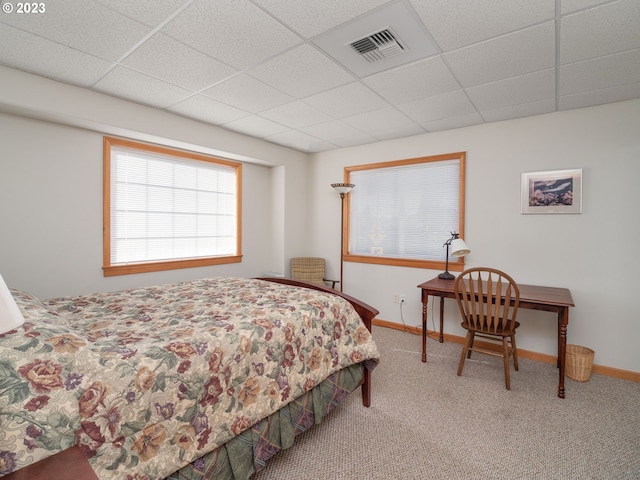 carpeted bedroom featuring a drop ceiling