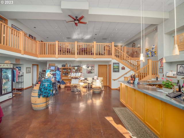 interior space featuring dark tile flooring, a drop ceiling, ceiling fan, and a high ceiling