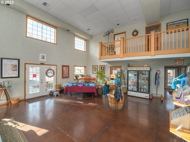 interior space featuring dark tile flooring, french doors, a drop ceiling, and a towering ceiling