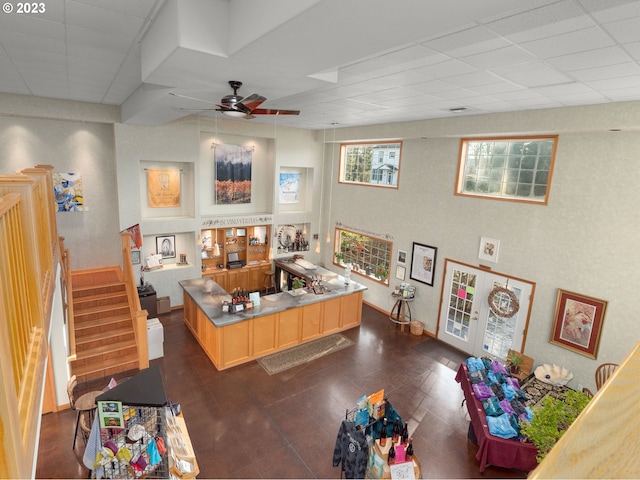 living room with a drop ceiling and ceiling fan