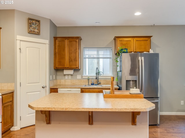 kitchen featuring a breakfast bar, stainless steel refrigerator with ice dispenser, light countertops, and a center island