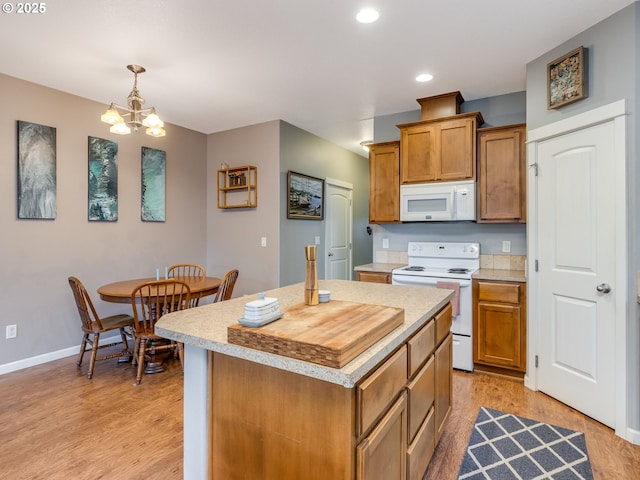 kitchen with decorative light fixtures, light countertops, brown cabinetry, a kitchen island, and white appliances