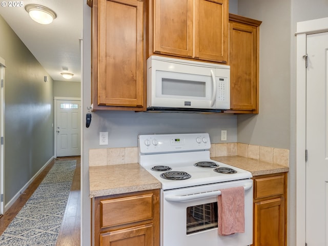 kitchen featuring brown cabinets, white appliances, and light countertops