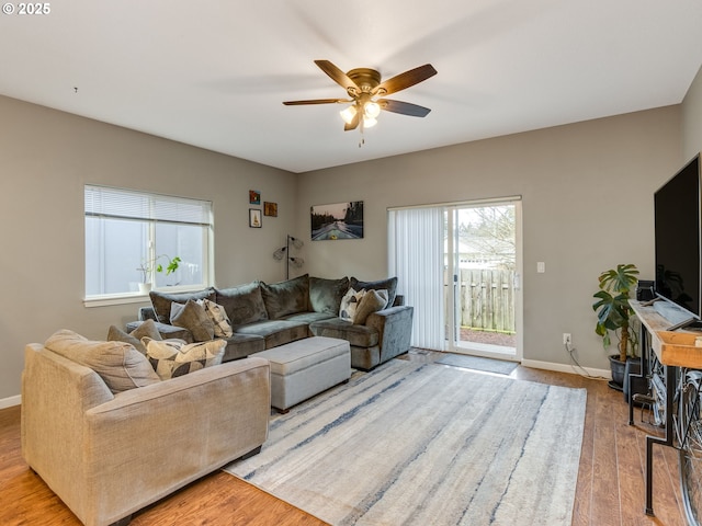 living room with light wood finished floors, a ceiling fan, and baseboards