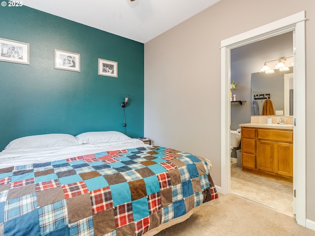 bedroom featuring light carpet, a sink, ensuite bath, and baseboards