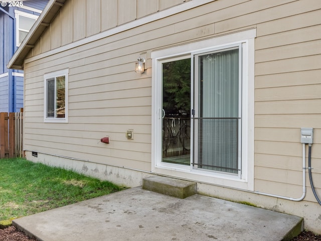 entrance to property with crawl space, a patio area, and board and batten siding