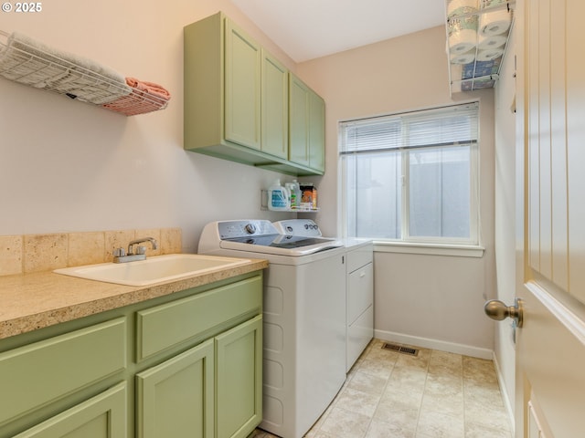 laundry area featuring separate washer and dryer, a sink, visible vents, baseboards, and cabinet space