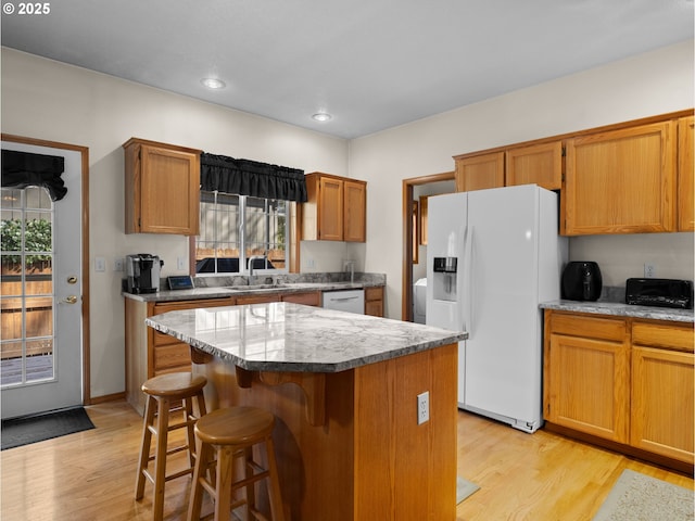 65679 E Alpine Way, Rhododendron, OR 97049 - kitchen with light wood finished floors, white appliances, brown cabinetry, a kitchen bar, and a kitchen island