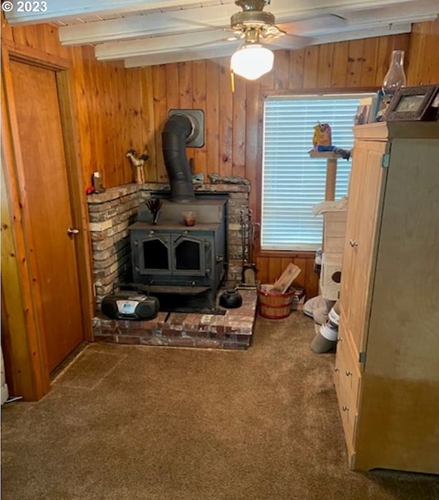 4590 Perpetua St, Florence, OR 97439 - detailed view of carpet, a wood stove, wooden walls, a ceiling fan, and beam ceiling