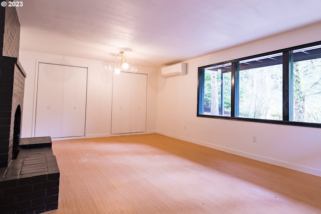 unfurnished living room with a brick fireplace, an AC wall unit, and a notable chandelier