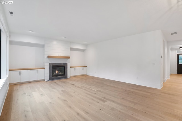 unfurnished living room with light wood-type flooring and a fireplace