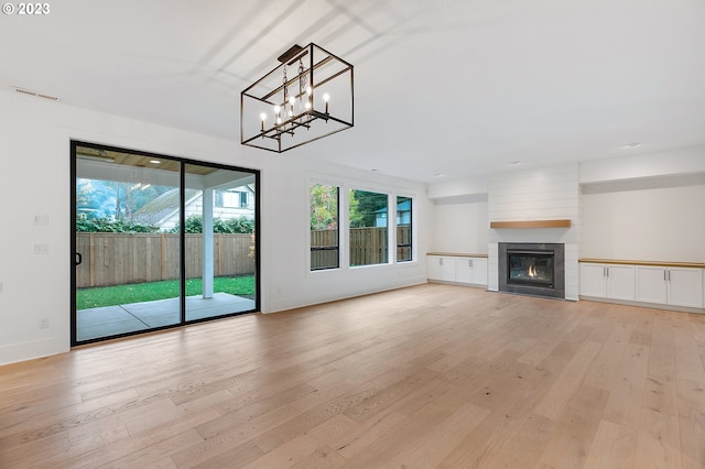 unfurnished living room featuring a notable chandelier, light hardwood / wood-style floors, and a large fireplace